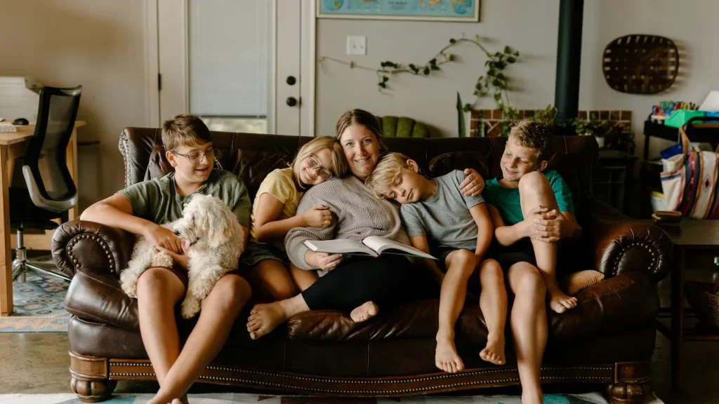 photo of family of five all sitting on the living room couch with their dog